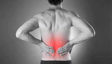 Man holding lower back in pain, highlighting areas of discomfort, relevant to back pain treatment at Desert Pine Chiropractic in Bellingham, WA.