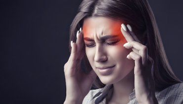 Woman experiencing headache, holding her head with tension, illustrating symptoms related to headaches and neck pain, relevant to chiropractic care for headache relief at Desert Pine Chiropractic in Bellingham, WA.