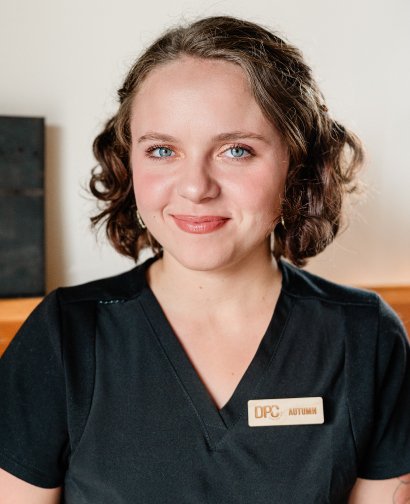 Chiropractic Assistant Autumn from Desert Pine Chiropractic, smiling and wearing a black uniform with a name tag.