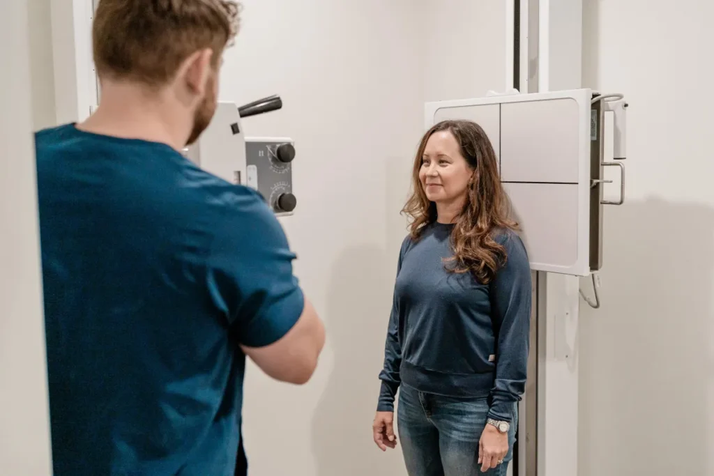 Chiropractor conducting digital X-ray assessment of a patient in a professional clinic setting, highlighting the use of advanced technology for spinal evaluation.
