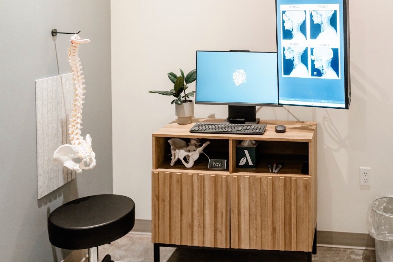 Chiropractic treatment room with a model spine, computer displaying diagnostic images, and a welcoming atmosphere for patient consultations at Desert Pine Chiropractic in Bellingham.